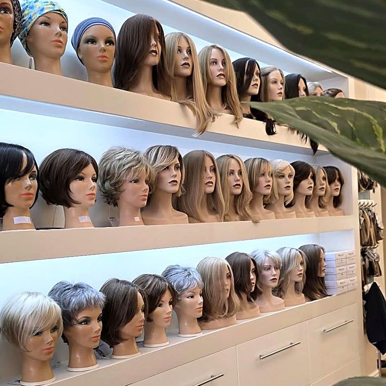 Perückenwand mit Modellen in vielen Farben und Längen