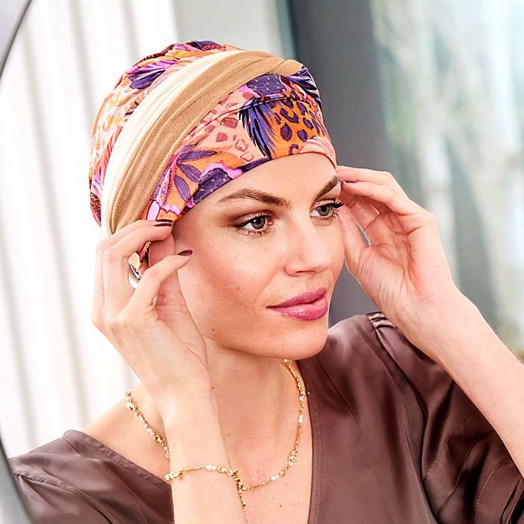 Frau richtet ihren bunt gemusterten Turban vor dem Spiegel