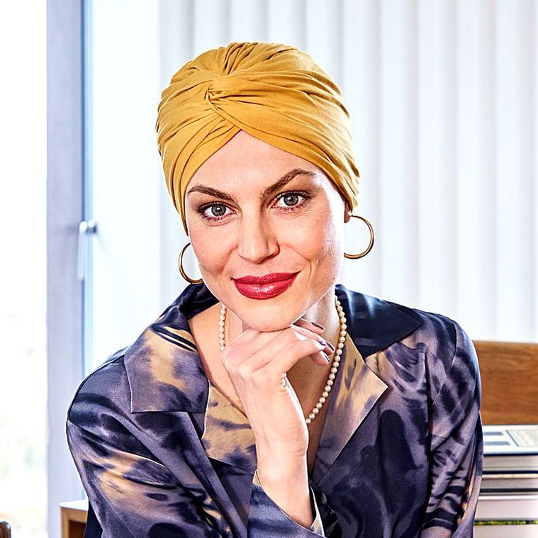 Frau mit senfgelbem Turban am Schreibtisch